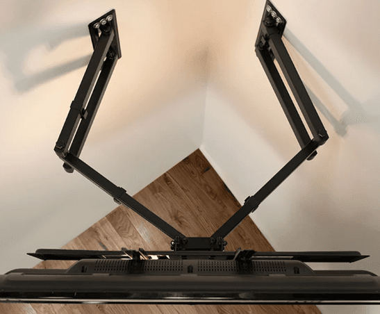 A corner-mount TV bracket's two arms extending diagonally into a room corner, viewed from below.